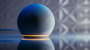 Close-up of a modern smart speaker in a stylish setting with illuminated base and reflection.