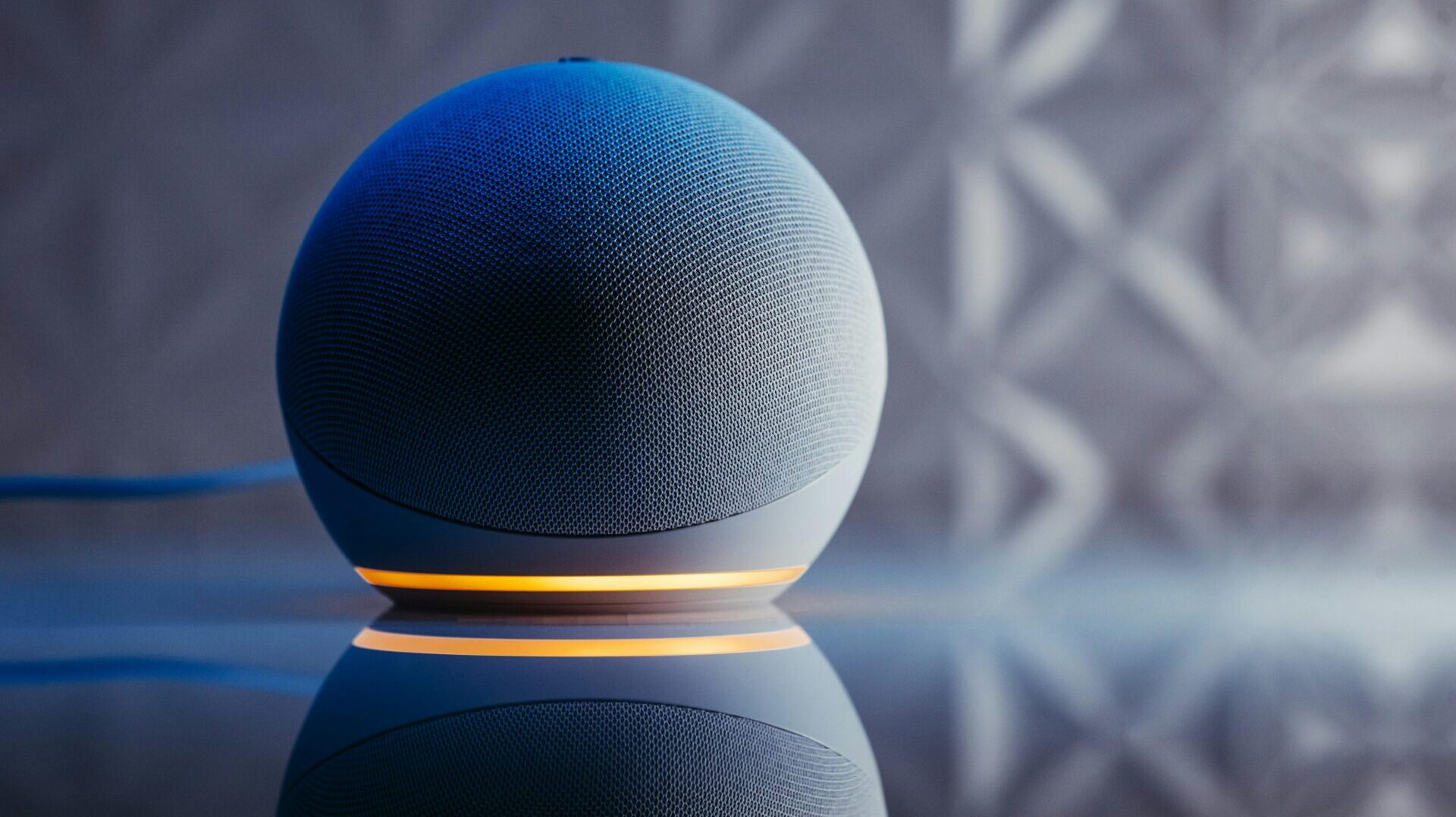 Close-up of a modern smart speaker in a stylish setting with illuminated base and reflection.